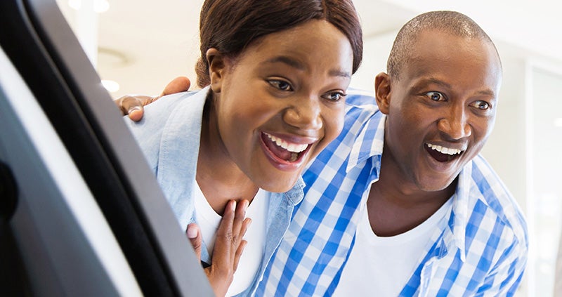 Two people looking inside a car